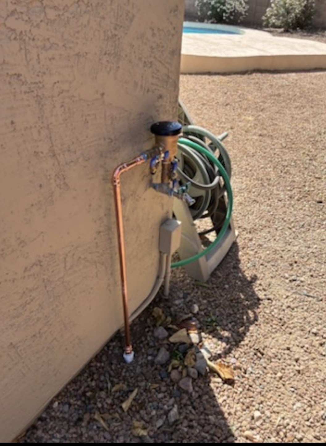 Outdoor copper plumbing and backflow prevention assembly beside a home on a Straight Flush Plumbing project